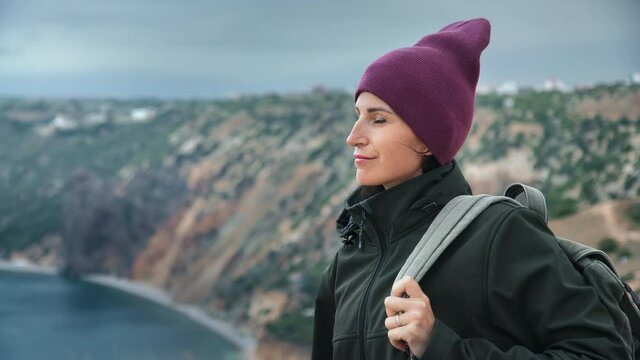 Happy woman tourist with backpack admiring nature sea scenery from top of high mountain