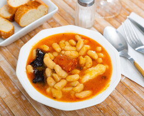 Traditional Asturian rich beans stew Fabada with pork shoulder, morcilla and chorizo served in...