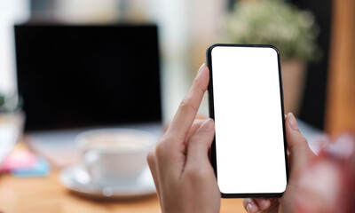 Mockup image blank white screen cell phone.women hand holding texting using mobile on desk at home office.
