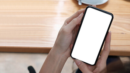 Mockup image blank white screen cell phone.women hand holding texting using mobile on desk at home office.