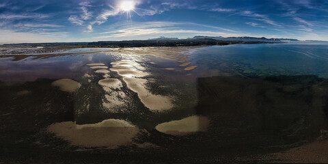 Marea baja carretera Austral de Chile, mucha arena, aves marinas y cordillera de los Andes.