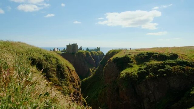 Cinematic view of the Dunnottar Castle, a medieval fortress on a rocky headland off the coast of Scotland, UK dating to 1400