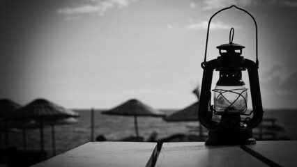 A retro kerosene lamp on the table in a seaside restaurant, black and white