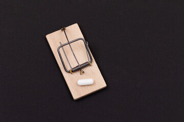 Pharmaceutical Addiction or Big Pharma Trap - White Pill in Wooden Mousetrap on Black Background
