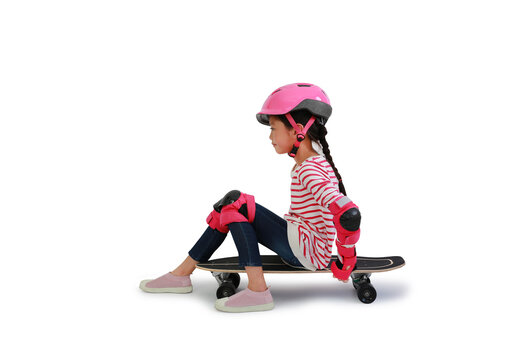 Caucasian young girl skateboarder with wearing safety and protective equipment sit on skateboard isolated on white background. Image with Clipping path
