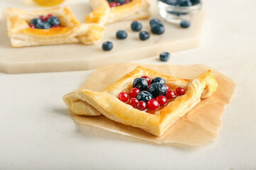 Danish pastry with fruit jam and berries on light background