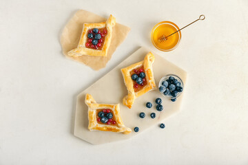Danish pastry with fruit jam and berries on light background