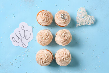 Tasty cupcakes and wedding rings on color background