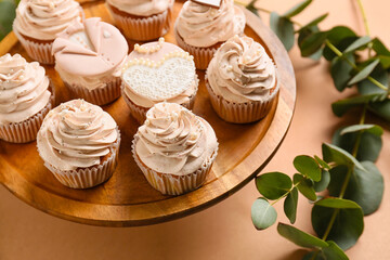 Dessert stand with tasty wedding cupcakes on color background