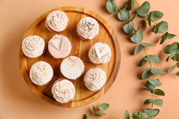 Fototapeta na wymiar Dessert stand with tasty wedding cupcakes on color background