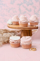 Tasty cupcakes and wedding rings on table