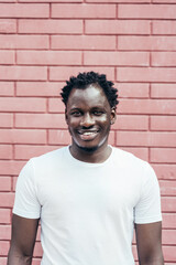 Portrait of Handsome smiling young African man over a pink brick wall