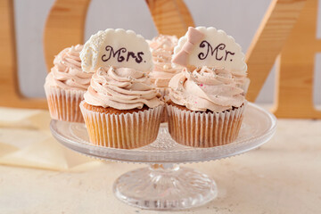 Dessert stand with tasty wedding cupcakes on table