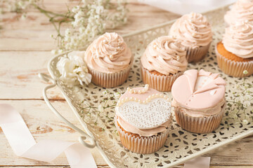 Fototapeta na wymiar Tray with tasty wedding cupcakes on white wooden background