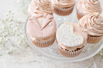 Obraz na płótnie Canvas Dessert stand with tasty wedding cupcakes on light background