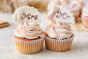 Tasty wedding cupcakes on light background