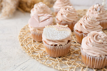 Tasty wedding cupcakes on light background