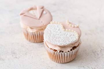 Tasty wedding cupcakes on light background