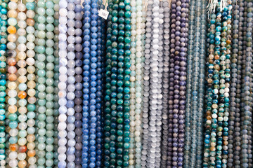 Multicolored beads made of gems strung on thread displayed on stand in store of jewelry accessories