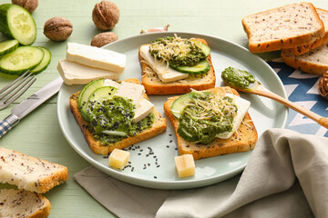 Tasty toasts with pesto sauce on color wooden background