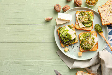 Tasty toasts with pesto sauce on color wooden background