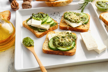 Tasty toasts with pesto sauce on light background, closeup