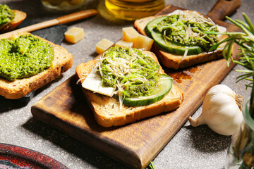 Tasty toasts with pesto sauce on grunge background, closeup