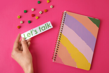 Woman and paper with text LET'S TALK, notebook and cubes on color background