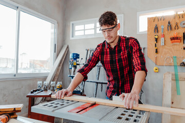 young caucasian carpenter cutting wooden board