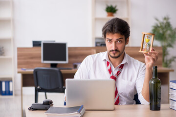 Young alcohol addicted male employee in time management concept