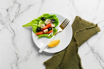 Plate with tasty Greek salad on light background