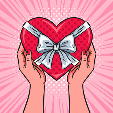 Hands holding red heart shaped box, gift, present with a bow and ribbons. Valentine's Day concept. Pop art vector comic illustration. Top view.	
