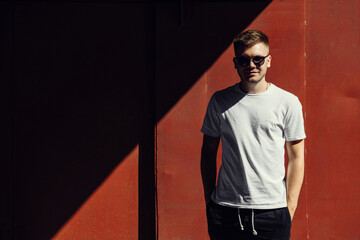 portrait of a young man in sunglasses near the orange wall with copy space