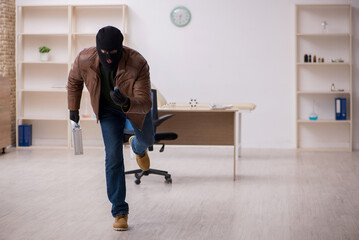 Young man in balaclava stealing vaccine from the lab