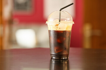Plastic cup with tasty iced coffee on table