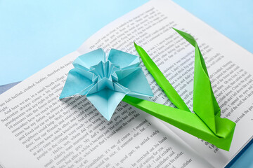 Book with origami narcissus on color background