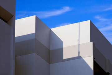 Sunlight and shadow on surface of white building  against blue sky background