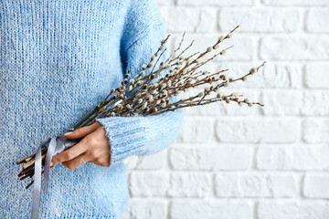 Woman holding willow branches near brick wall © Pixel-Shot