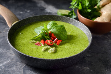 Frying pan with tasty green chicken curry on grunge background