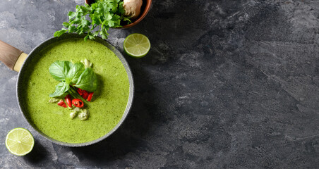 Frying pan with tasty green chicken curry on grunge background