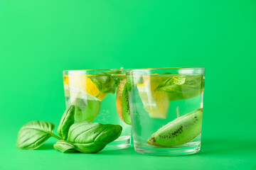 Glasses of tasty lemonade with basil on color background