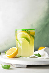 Glass of tasty lemonade with basil on light background