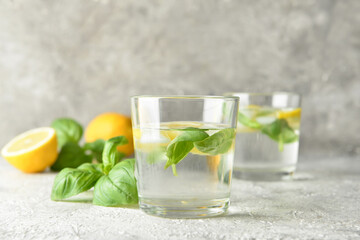 Glasses of tasty lemonade with basil on light background