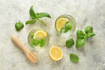 Glasses of tasty lemonade with basil on light background