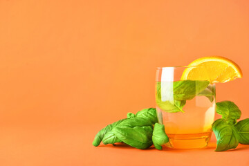Glass of tasty lemonade with basil on color background