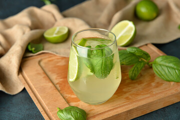 Glass of tasty lemonade with basil on dark background