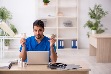 Young male doctor suggesting pills in the clinic