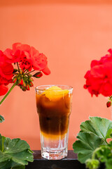 Espresso tonic with ice in a highball glass garnished with an orange zest