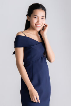 Image of portrait. Asian woman wearing a blue dress and smiling poses before taking a picture with a LED light in a white room at the studio. Concept model posing in studio.
