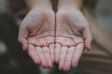 Close-up of both hands of a child who is holding hands in hopes of receiving something.